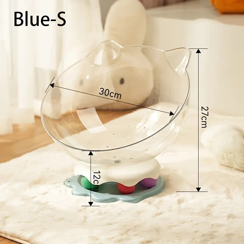 A blue acrylic capsule-shaped cat bowl, with a track ball which is placed on a white rug
