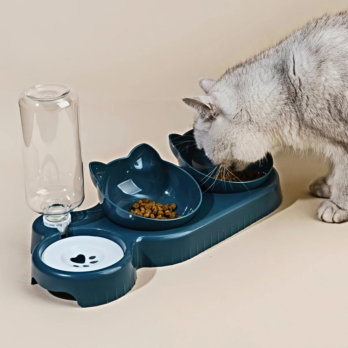 Cat using a blue pet feeder with water bottle and two bowls on a beige surface.