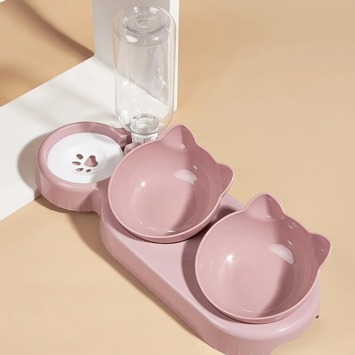 Pink pet bowl set with two bowls and a water bottle on a beige background