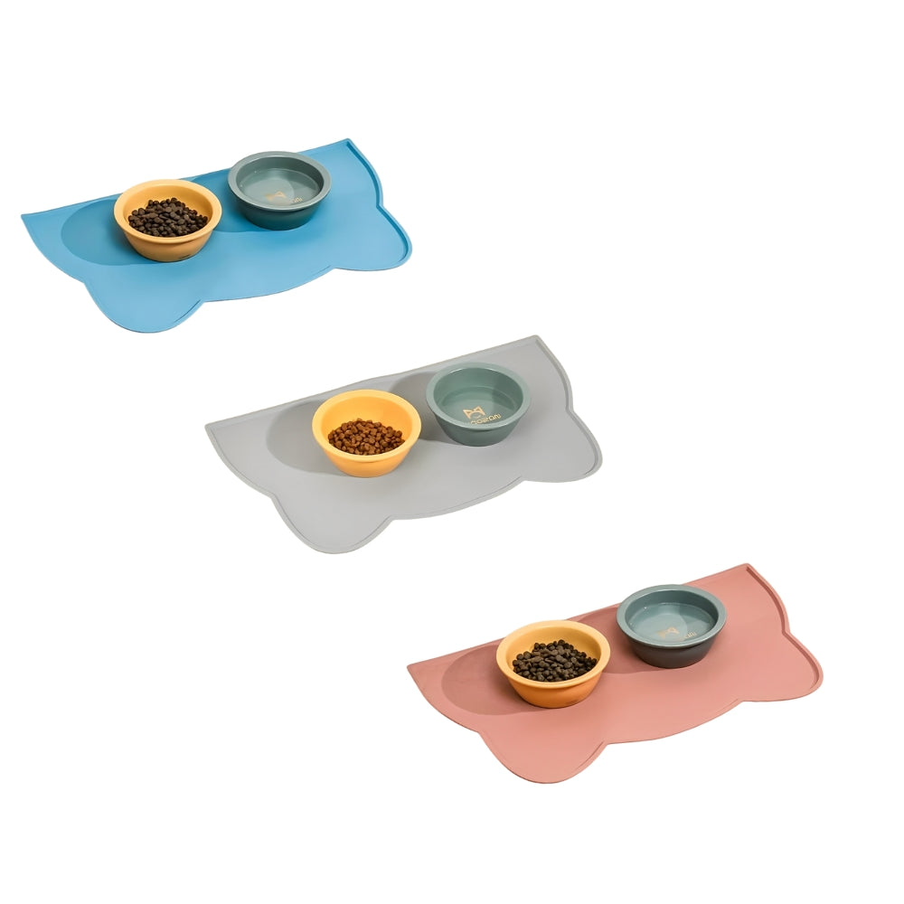 Three pet silicone mats in blue, gray, and pink with two bowls on top on a white background