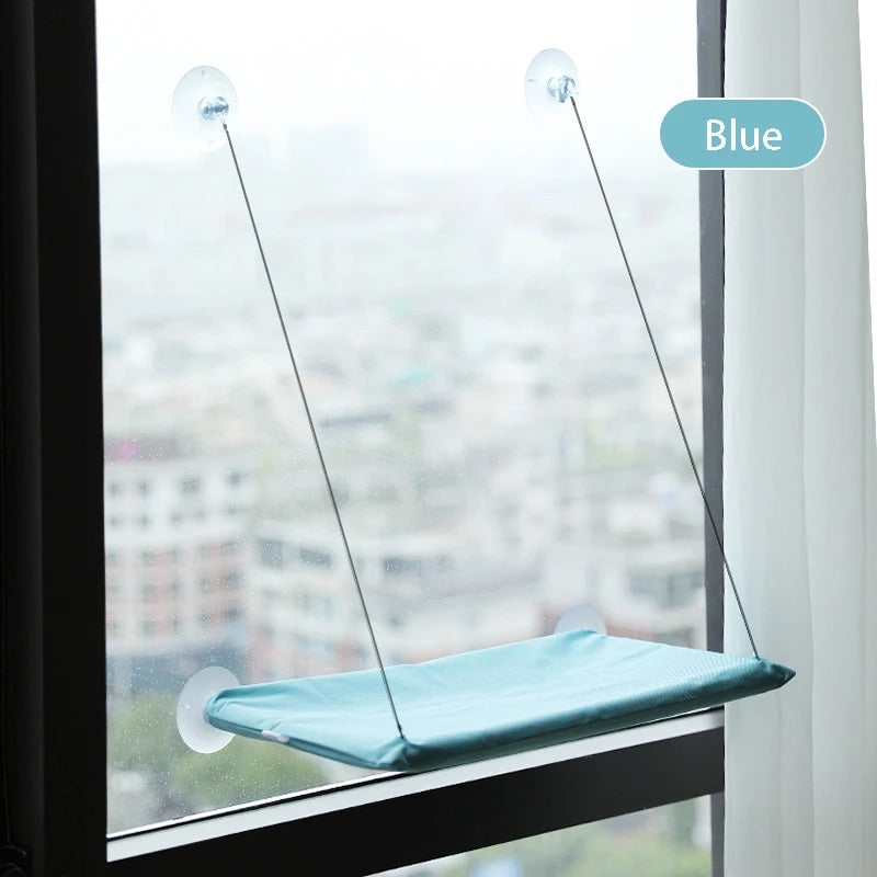 Blue window pet perch attached to a glass pane with a blurred cityscape background