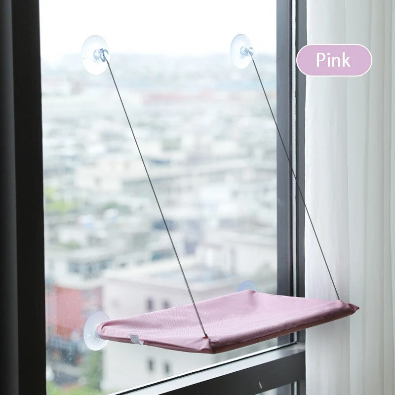 Pink window pet hammock attached to a window with suction cups