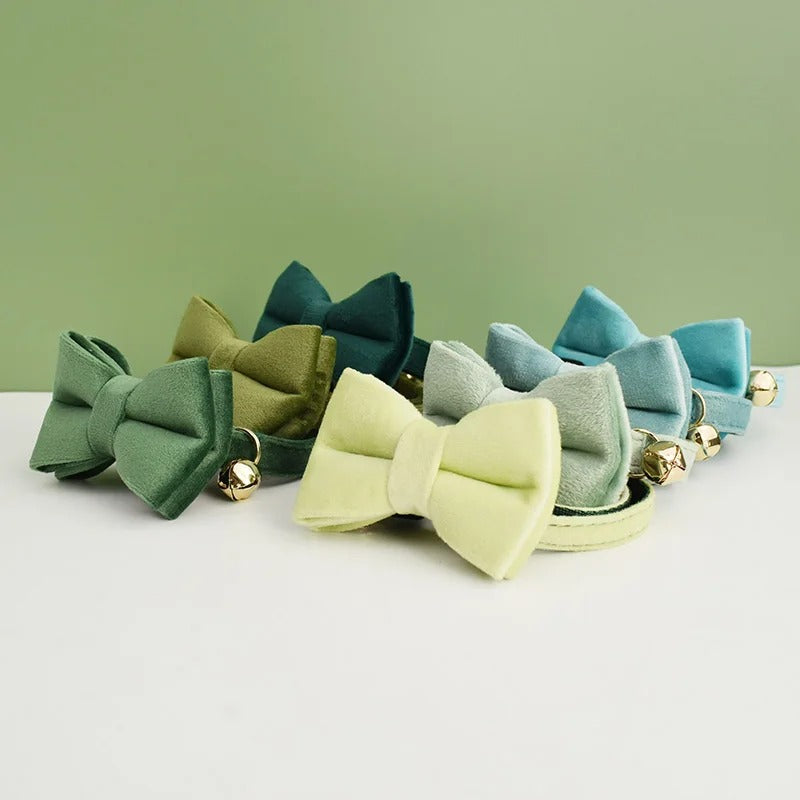 Set of colorful bow-shaped cat collars on a white surface with a green background