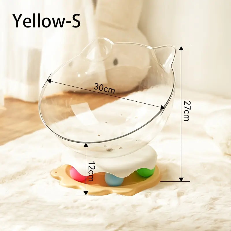 A yellow acrylic capsule-shaped cat bowl, with a track ball which is placed on a white rug