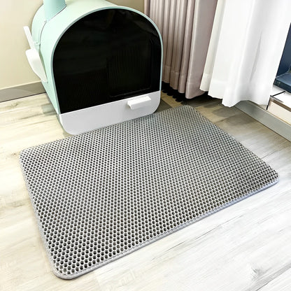 A grey non-slip waterproof cat litter mat with a honeycomb texture, shown in front of the cat litter box.
