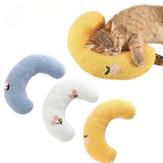Cat lying on a yellow crescent-shaped cushion with other cushions in blue, white, and yellow below.