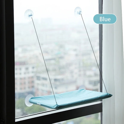 Blue window pet perch attached to a glass pane with a blurred cityscape background