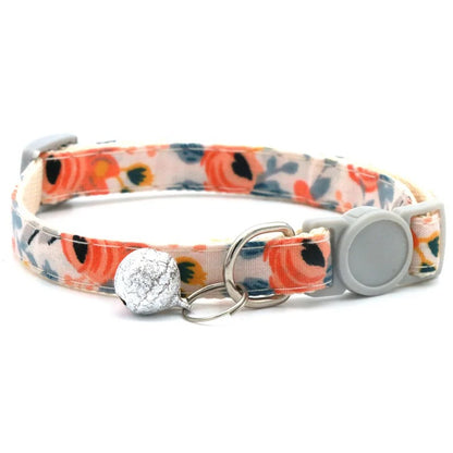 Floral patterned dog collar with a silver bell and clip on a white background
