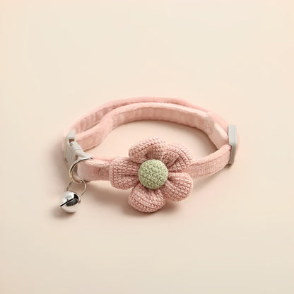 A crochet cat collar in pink with a buckle for adjustability on a beige background