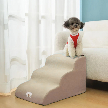 Dog using a set of pet stairs to climb onto a couch in a home setting.
