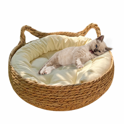 A cozy rattan cat bed with a soft white cushion, constructed with a sturdy paper rope frame and featuring a natural brown rattan finish with a cat lying on it.