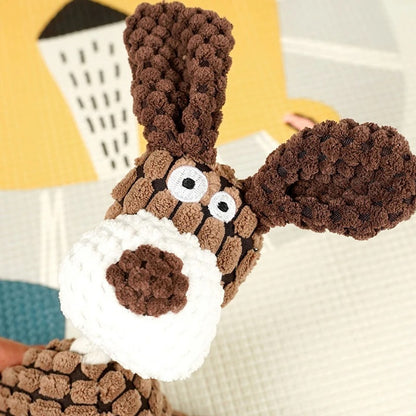 Close-up of a brown and white knitted toy resembling a dog's face with a blurred background.