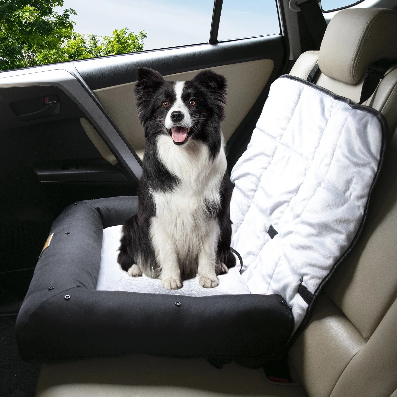Dog sitting on a pet seat cover in a car with a white blanket